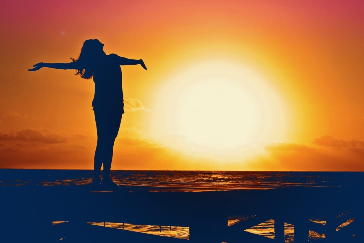 CatSci’s Commitment to Wellbeing: Image of shadowed woman at sunset with arms outstretched