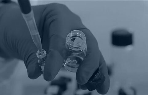 CatSci blog - Tactics for addressing the problem of poor drug solubility in solid oral dosage formulations - Dark blue tinged image of a pipette and glass bottle in gloved hands