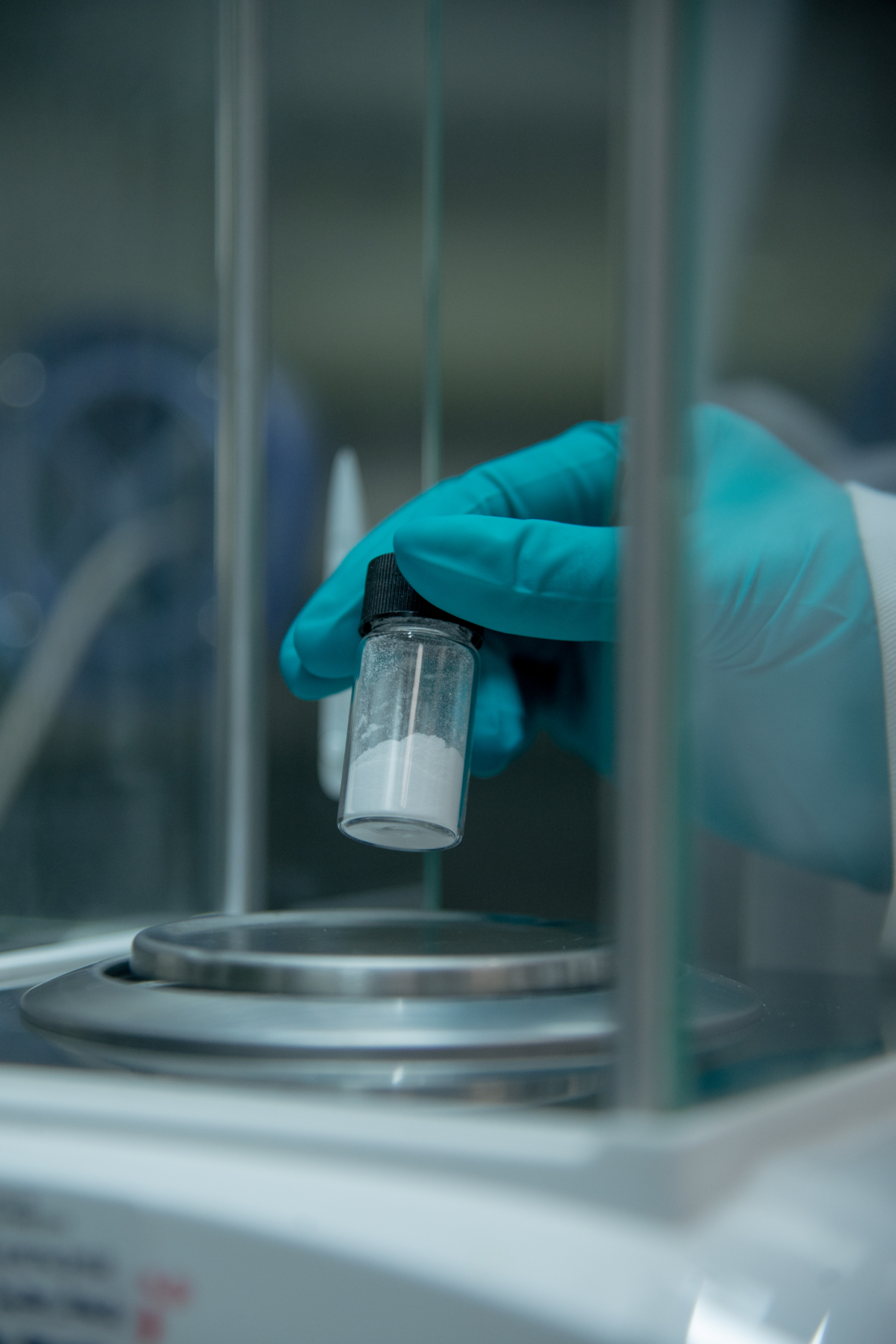 Image of a gloved hand holding a vial of powder